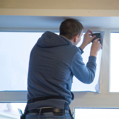 Une personne installe un film effet miroir sur une vitre