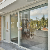 Un hall d'entrée d'immeuble avec un film miroir argentée sur les vitres